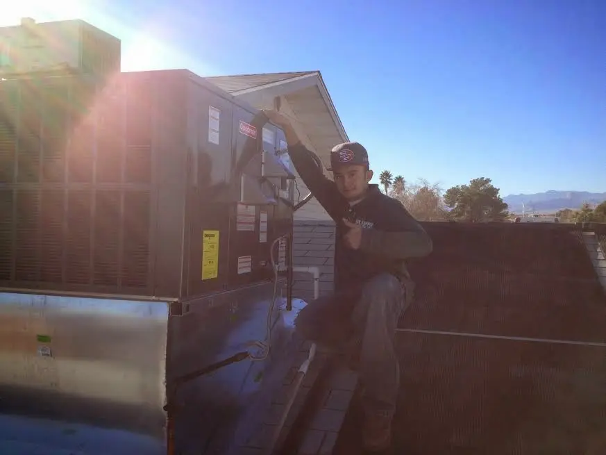 HVAC technician performing Air Duct Cleaning on a rooftop unit in Yorktown